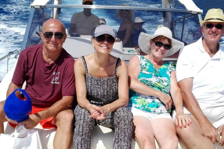 Four people sitting on a boat smiling on a sunny day.