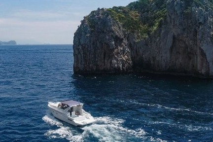 Boat sailing near a large rocky island in the ocean.