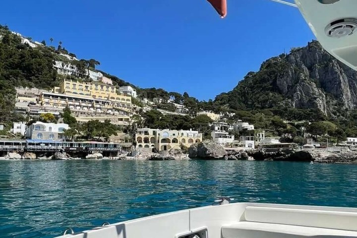 View of coastline with buildings and cliffs from a boat on the water.