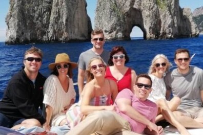 Group of people on a boat in front of large rock formations in the sea.