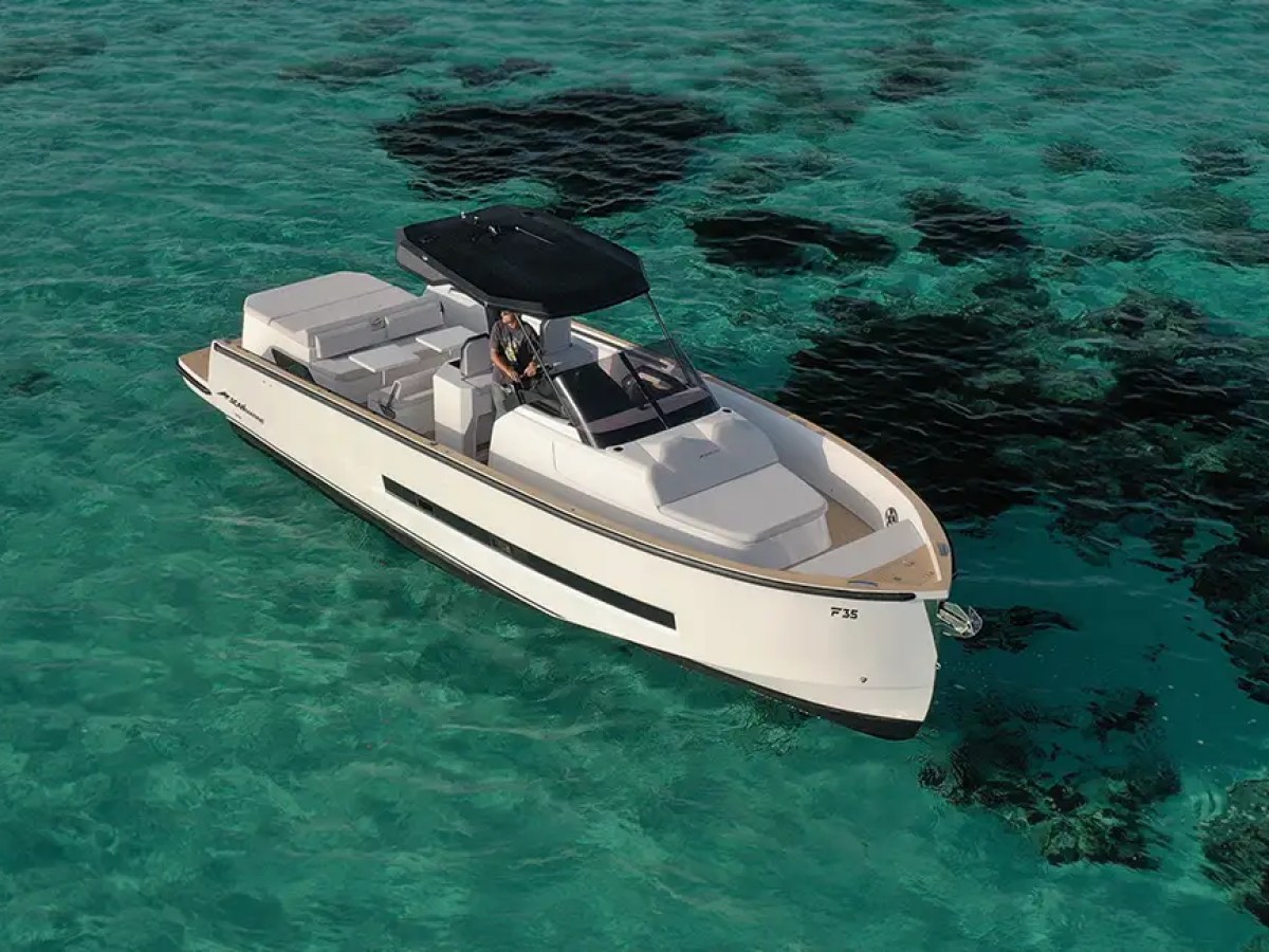 White motorboat with black canopy on clear turquoise water with dark patches.
