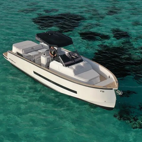 White motorboat with black canopy on clear turquoise water with dark patches.