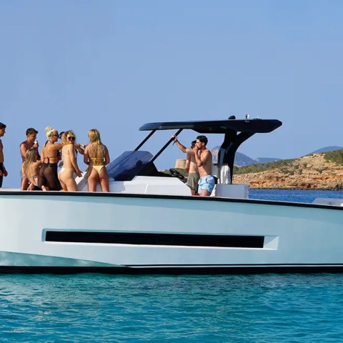 Group of people enjoying a day on a yacht in clear blue water.