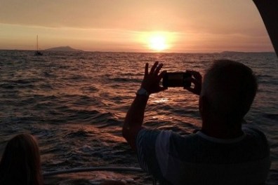 Person taking photo of sunset over the ocean from a boat.