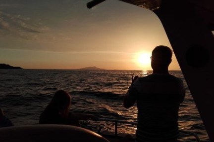 Silhouettes on a boat at sunset with ocean view.