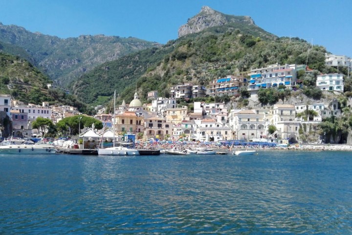 Coastal town with colorful buildings and mountains in the background.