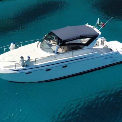 White motorboat with a dark canopy on clear blue water.