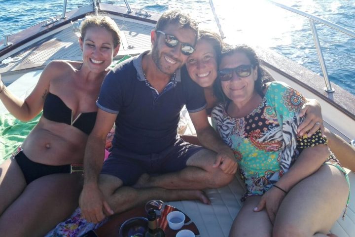 Four people sitting on a boat deck, smiling at the camera.
