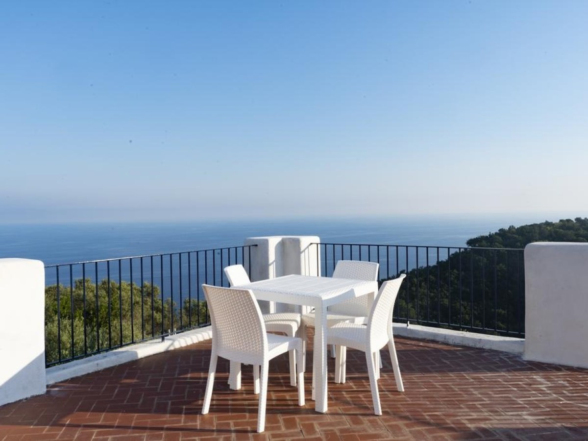 Outdoor patio with white table and chairs overlooking ocean view.