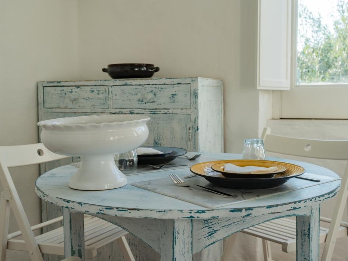 Rustic dining area with round table, two chairs, and a large bowl.