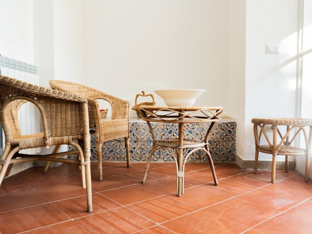 Cozy nook with wicker chairs, table, and a ceramic bowl on tiled floor.