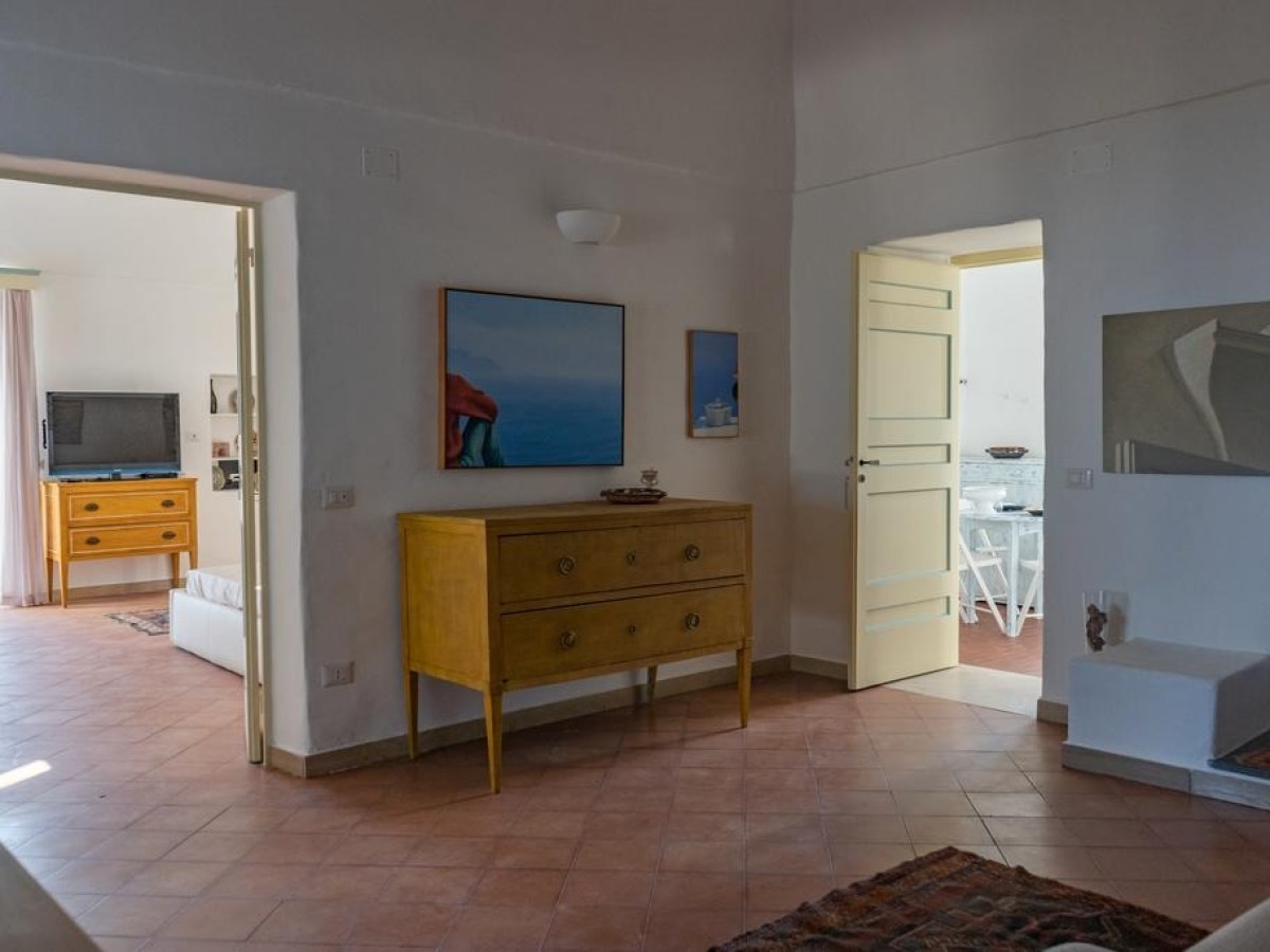 Spacious living area with light walls, wooden dresser, and two doors leading to other rooms.