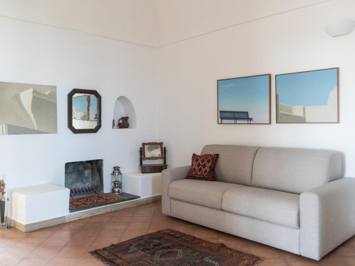 Living room with beige sofa, wall art, and decorative rugs on tiled floor.
